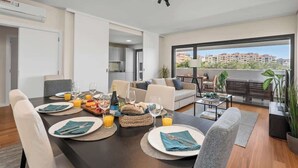 Un salon moderne avec un coin repas, un balcon offrant une vue agréable et une cuisine en arrière-plan.