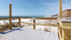 A wooden deck with a metal safety grid, overlooking a beach with a clear sky. - 3BR ~ Beachfront ~ Huge Balcony ~ 2 Pools ~ Luxury (Fort Walton Beach)