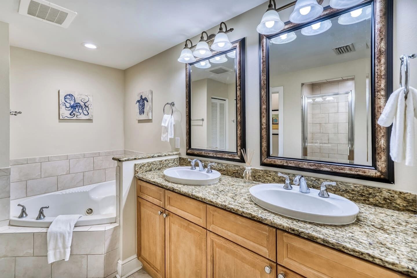 A bathroom with two sinks, a bathtub, and a large mirror with lights.