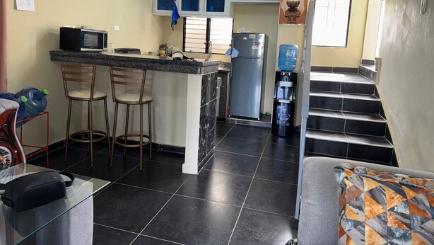 Una cucina compatta con forno a microonde, frigorifero e sgabelli da bar.