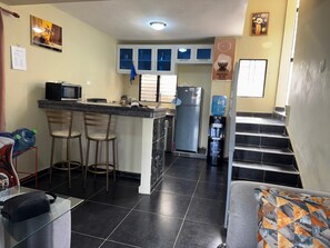 Eine kleine Küche mit Mikrowelle, Kühlschrank und Barhocker.