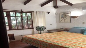 Een slaapkamer met een bed, een raam, een ventilator en een kunstwerk aan de muur.