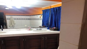 Een badkamer met een witte wastafel, donkere houten kastjes en een blauw douchegordijn.