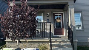 A two-story house with a front porch, a mailbox, and two trash bins. - ✨your home away from home✨Modern
Comfort in a spacious 3-Bedroom Townhome (Airdrie)