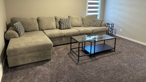 A living room with a sectional sofa, a glass coffee table, and a window with blinds. - ✨your home away from home✨Modern
Comfort in a spacious 3-Bedroom Townhome (Airdrie)