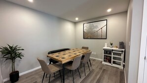 A dining area with a wooden table and chairs, a potted plant, and a cabinet with kitchenware. - ✨your home away from home✨Modern
Comfort in a spacious 3-Bedroom Townhome (Airdrie)