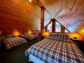 A cozy attic bedroom with wooden walls and sloped ceilings, featuring three beds with plaid bedding and wall-mounted lamps. - Golden Rustic Cabin Getaway|Loft & Mountain Views! (Golden)