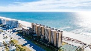 A high-rise hotel with multiple floors, a parking lot, and a beach view. - Beachfront Penthouse 1BR @ Phoenix X • Sleeps 6 • Stunning Views & Next to Flora-Bama (Orange Beach)