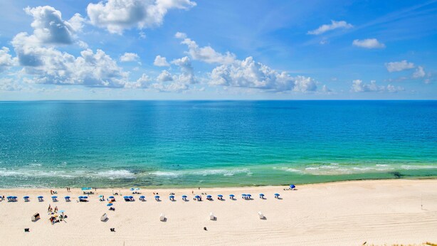 A beach with clear blue water, white sand, and a few umbrellas. - Beachfront Penthouse 1BR @ Phoenix X • Sleeps 6 • Stunning Views & Next to Flora-Bama (Orange Beach)