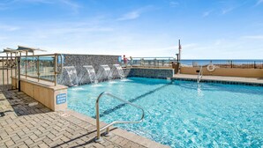 A swimming pool with a tiled deck, a lifeguard stand, and a view of the ocean. - Beachfront Penthouse 1BR @ Phoenix X • Sleeps 6 • Stunning Views & Next to Flora-Bama (Orange Beach)