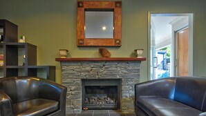 A living room with a stone fireplace, two leather sofas, a wooden mantelpiece, and a mirror above the fireplace. - Cute As, by the lake, bike tracks walking distance to shops & retail !! (Queenstown)