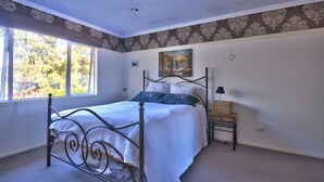 A bedroom with a bed, a nightstand, a lamp, and a window with a view of trees. - Cute As, by the lake, bike tracks walking distance to shops & retail !! (Queenstown)