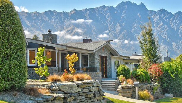A modern house with a stone facade, large windows, and a stone staircase leading to the entrance. - Cute As, by the lake, bike tracks walking distance to shops & retail !! (Queenstown)
