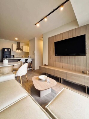 Ein modernes Wohnzimmer mit Flachbildfernseher, Couchtisch aus Holz und einer Couch.