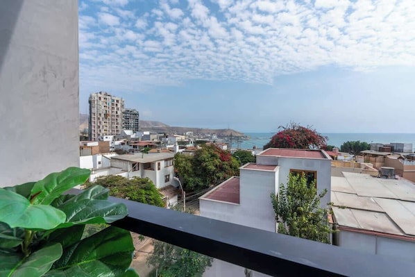 Un balcón con vista a una ciudad costera, incluyendo edificios y un cielo despejado.