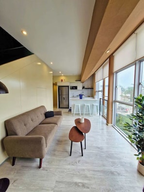 Uma sala de estar moderna com um sofá, uma mesa pequena e vista para a cozinha e a sala de jantar.