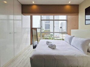 Ein Hotelzimmer mit einem großen Bett, einem Kleiderschrank und einem Fenster mit Blick auf Gebäude.