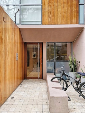Ein modernes Gebäude mit Holzfassade, Glastür und einem Fahrrad davor.