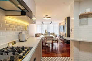 Een moderne keuken met een gasfornuis, witte metrotegels, en een eethoek met een ronde tafel en stoelen.