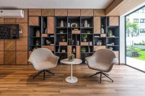 Ein modernes Interieur mit einer Holzwandverkleidung, zwei Stühlen, einem kleinen Tisch und einem großen Fenster.