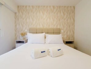 Ein Hotelzimmer mit einem Bett, zwei Kissen, einer Kopfteil und zwei Handtüchern mit dem Logo 'Geko'.