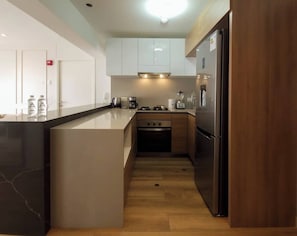 Eine moderne Küche mit einer zentralen Kochinsel, einem eingebauten Backofen und Edelstahlgeräten.