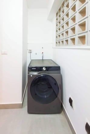 Ein kleiner Hauswirtschaftsraum mit einer Waschmaschine, einer Bedienkonsole und einer Steckdose.