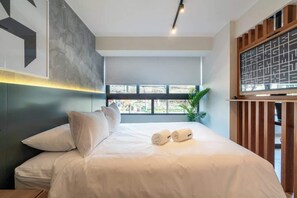 Ein modernes Hotelzimmer mit einem großen Bett, Blick durch das Fenster und einer dekorativen Wandverkleidung.
