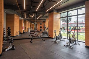 Une salle de sport équipée de matériel d’exercice, dotée de grandes fenêtres et d’un mur recouvert de miroirs.