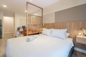 Ein Hotelzimmer mit einem großen Bett, einem Holzkopfende, einem Nachttisch mit Lampe und einem kleinen Tisch mit Stuhl.