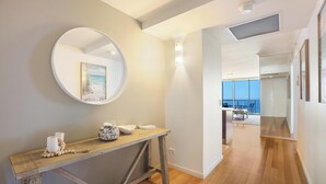 A modern interior with a wooden console table, a round mirror, and a framed artwork on the wall.