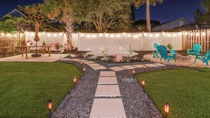 A backyard with a stone pathway, outdoor furniture, and string lights.