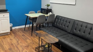 A modern living room with a black leather sofa, a wooden coffee table, and a dining table with chairs. - Private apartment(bedroom, living, kitchen, bath) (Pincourt)