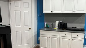 A compact kitchen with white cabinets, a black countertop, and a wooden floor. - Private apartment(bedroom, living, kitchen, bath) (Pincourt)