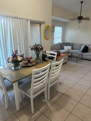 Un coin repas comprenant une table, des chaises, un vase de fleurs et un ventilateur de plafond.