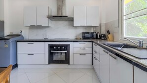 Une cuisine moderne avec des meubles blancs, un four encastré, un four à micro-ondes et un évier.
