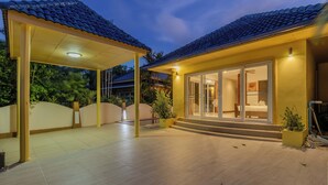Une maison moderne dotée d’un patio couvert, d’une grande porte vitrée donnant accès à une chambre et d’un toit recouvert de tuiles.