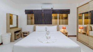 Une chambre d’hôtel avec un grand lit, une table de chevet avec une lampe, une armoire, un miroir et un appareil de climatisation.