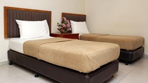 A hotel room with two beds, a nightstand, and a vase with flowers. - Hotel Rembia (Sungei Petai)