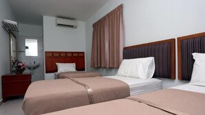 A hotel room with three single beds, a wooden headboard, a dresser, and a mirror. - Hotel Rembia (Sungei Petai)