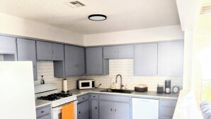A compact kitchen with grey cabinets, a white refrigerator, a stove, an oven, and a microwave. - Game Day Getaway 1 | Walk to OSU | Prime Location (STILLWATER)