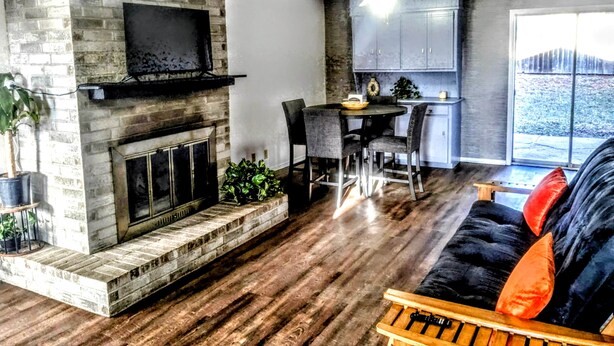 A living room with a fireplace, a dining area, and a kitchen. - Game Day Getaway 1 | Walk to OSU | Prime Location (STILLWATER)