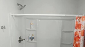 A bathroom with a shower, a toilet, and a sink. There are two shelves with toiletries. - Game Day Getaway 1 | Walk to OSU | Prime Location (STILLWATER)