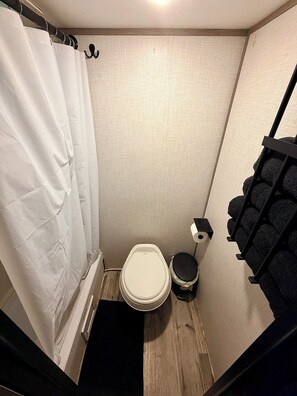 Ein kleines, kompaktes Badezimmer mit Toilette, einer Duschvorhang und einem schwarzen Handtuchhalter.