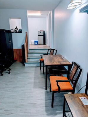 A conference room with a wooden table and orange chairs, a black office chair, and a refrigerator in the background. - The Sitka Suite | Central Apartment, Waterfront, 2 Beds (Alert Bay)