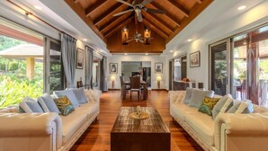 A spacious living room with a high ceiling, wooden beams, and a central coffee table.