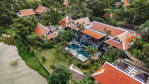 An aerial view of a resort with multiple buildings, a swimming pool, and lush greenery.