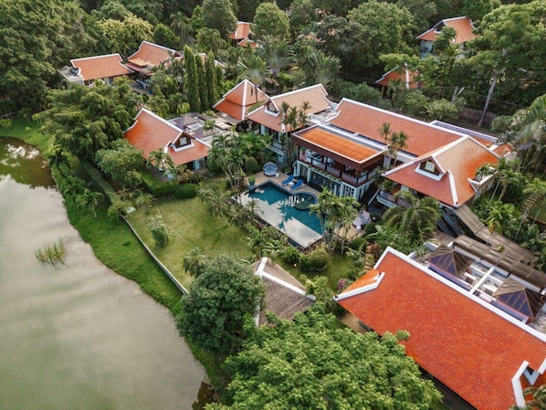 An aerial view of a resort with multiple buildings, a swimming pool, and lush greenery.