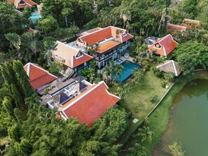 An aerial view of a resort with multiple buildings, a swimming pool, and lush greenery.