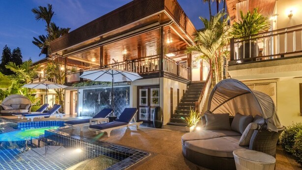 A two-story building with a swimming pool, outdoor seating, and a covered seating area.